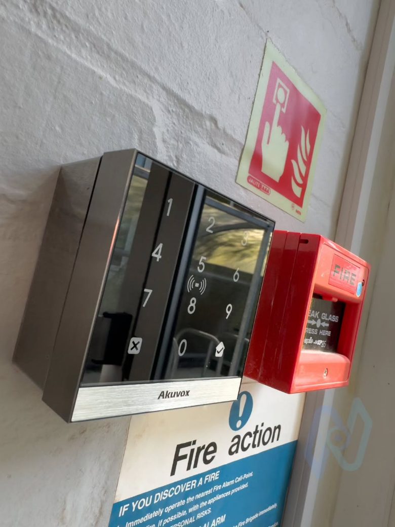 Akuvox A02 reader for staff PIN and NFC fob entry, beside a fire action sign