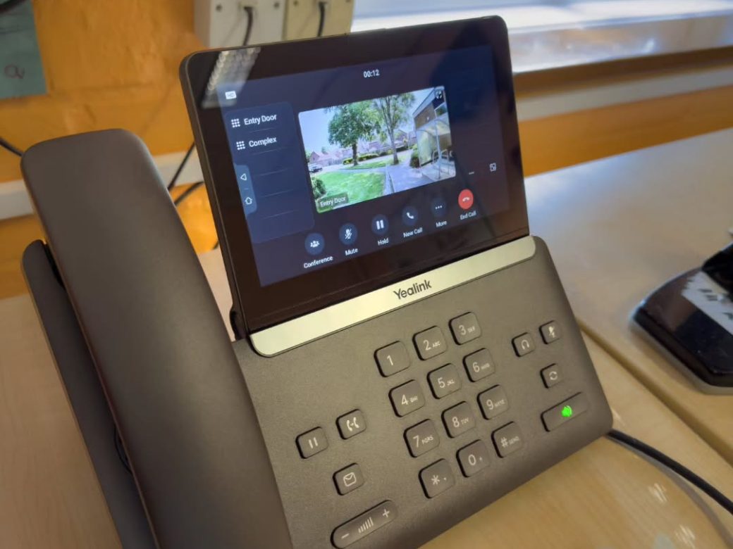 Yealink desk phone in the school office showing the live entry door camera during a visitor call