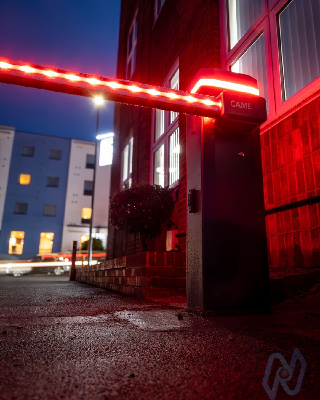 The barrier’s red-lit boom across the entrance at dusk