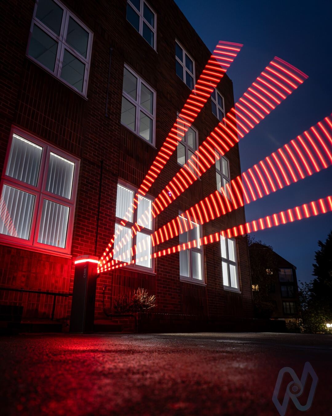 CAME Gard GT4 barrier at night, its illuminated boom glowing red, caught rising in a long exposure