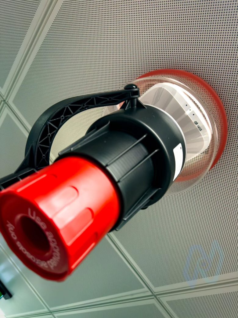 A Nova engineer testing a ceiling detector with a smoke tester pole during commissioning