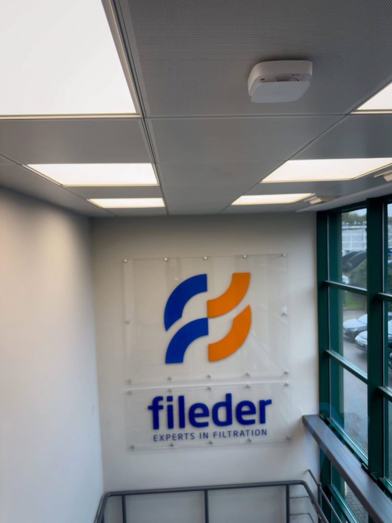 Wireless detector on the ceiling of the Fileder stairwell, with the Fileder logo on the wall