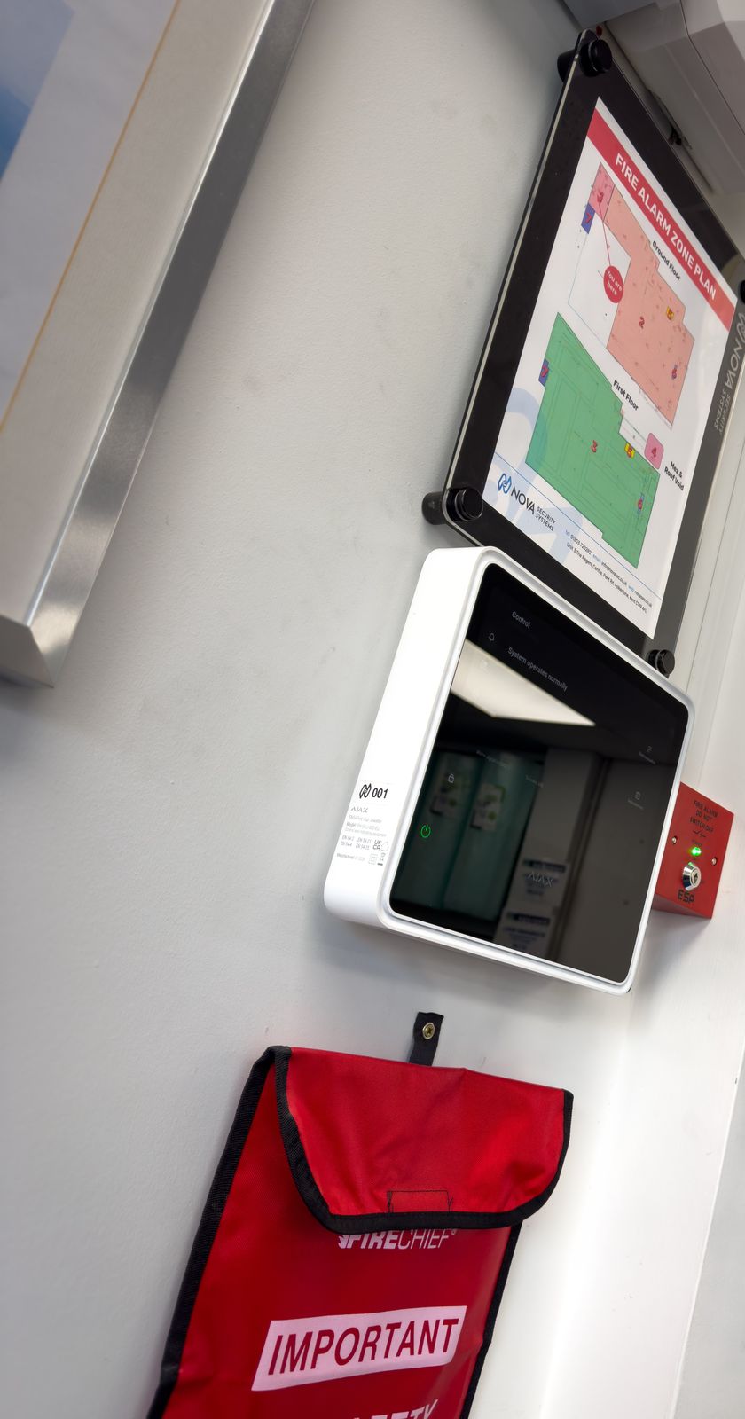 Ajax EN54 Fire Hub with a framed zone plan above it and a key switch beside it