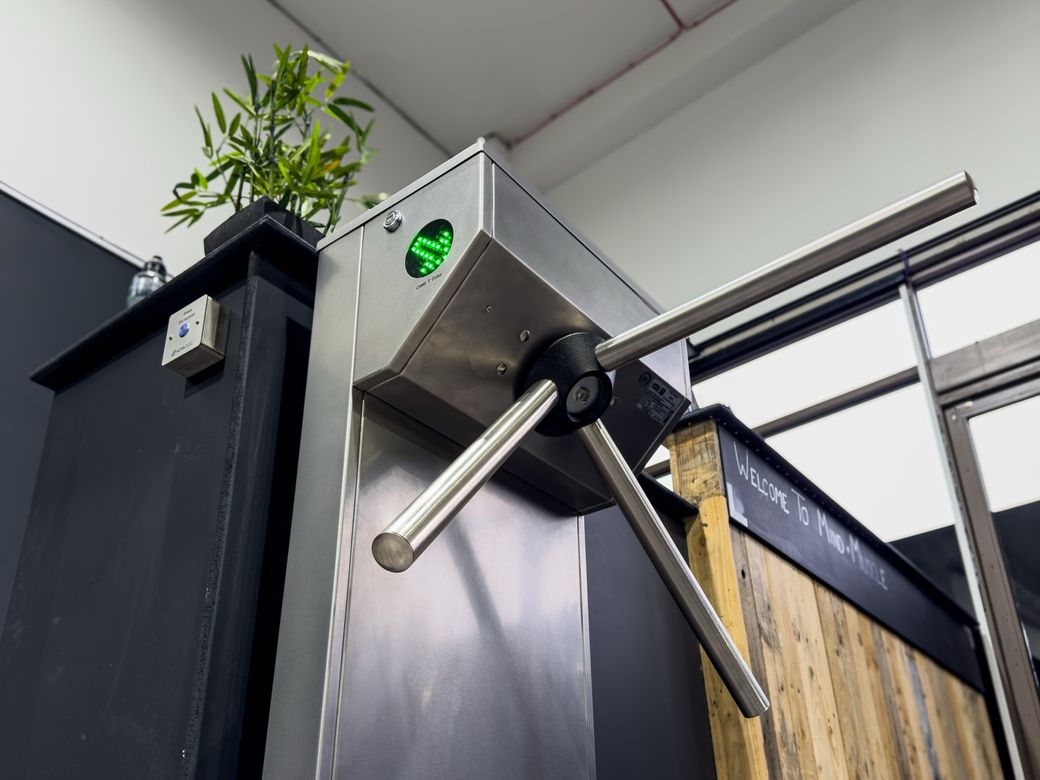 Stainless steel tripod turnstile with a green go light at Mind Muscle Fitness