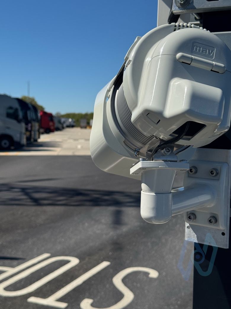 ANPR camera looking down a lane marked STOP, with parked trucks behind