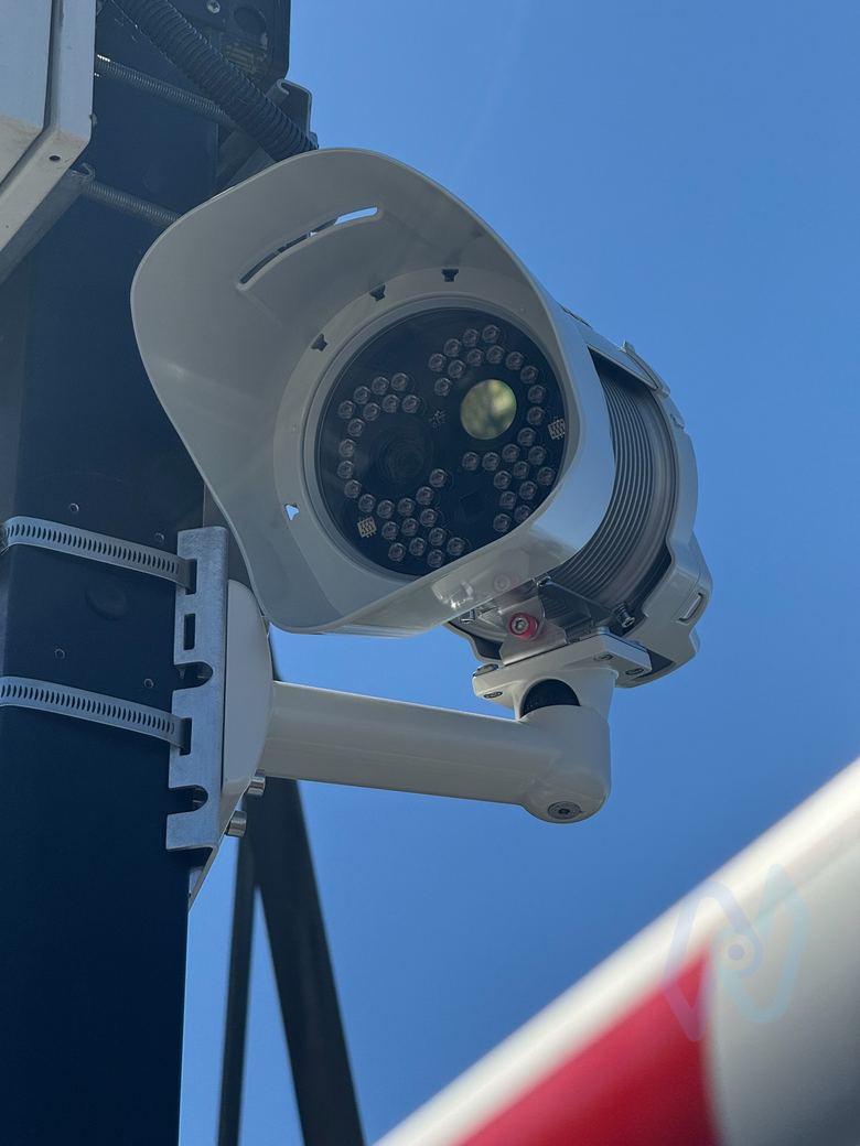 ANPR camera on a black post against a blue sky, with a barrier arm in front