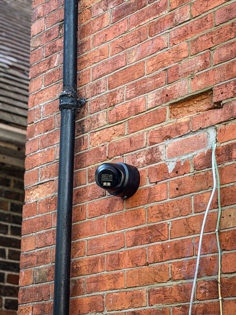 Black turret camera on the brick pier between the shop windows