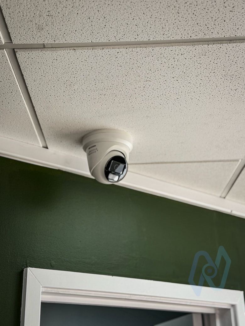 White turret camera in the soffit above the shop entrance