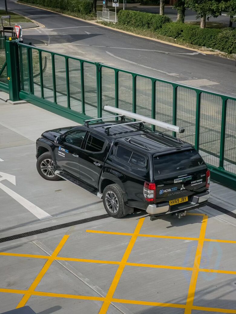 16 m green cantilever gate open beside the entrance, with a Nova pickup
