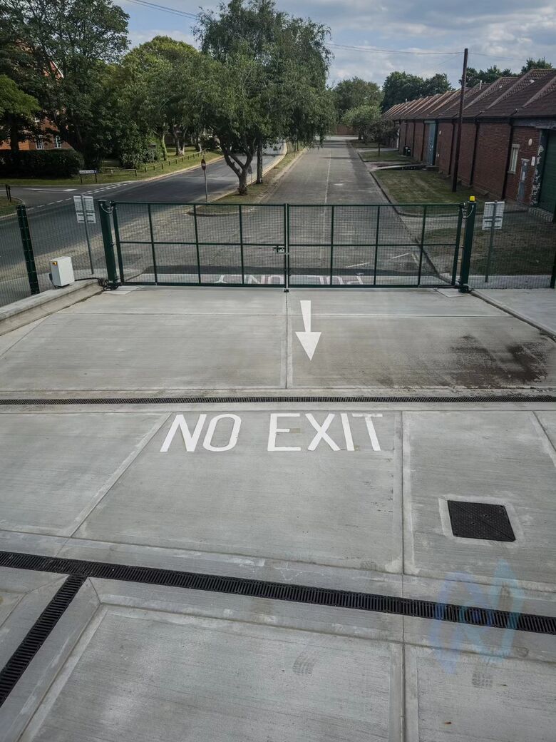 The pair of 10 m swing gates at the exit, with NO EXIT road markings