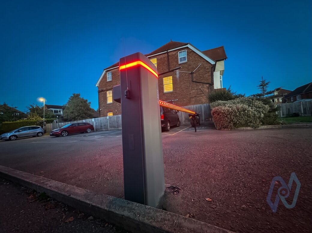 CAME Gard GT4 barrier at dusk in a Cheriton car park, its cabinet crown and boom lit red