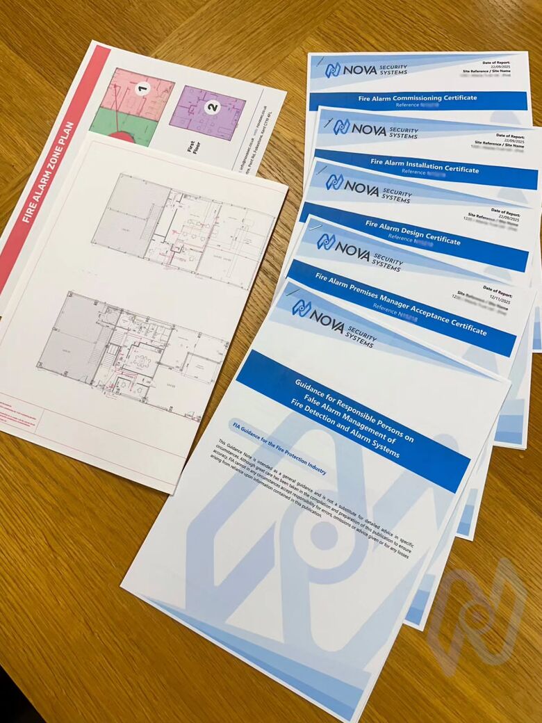 Nova fire alarm certificates, zone plans and false alarm guidance laid out on a desk
