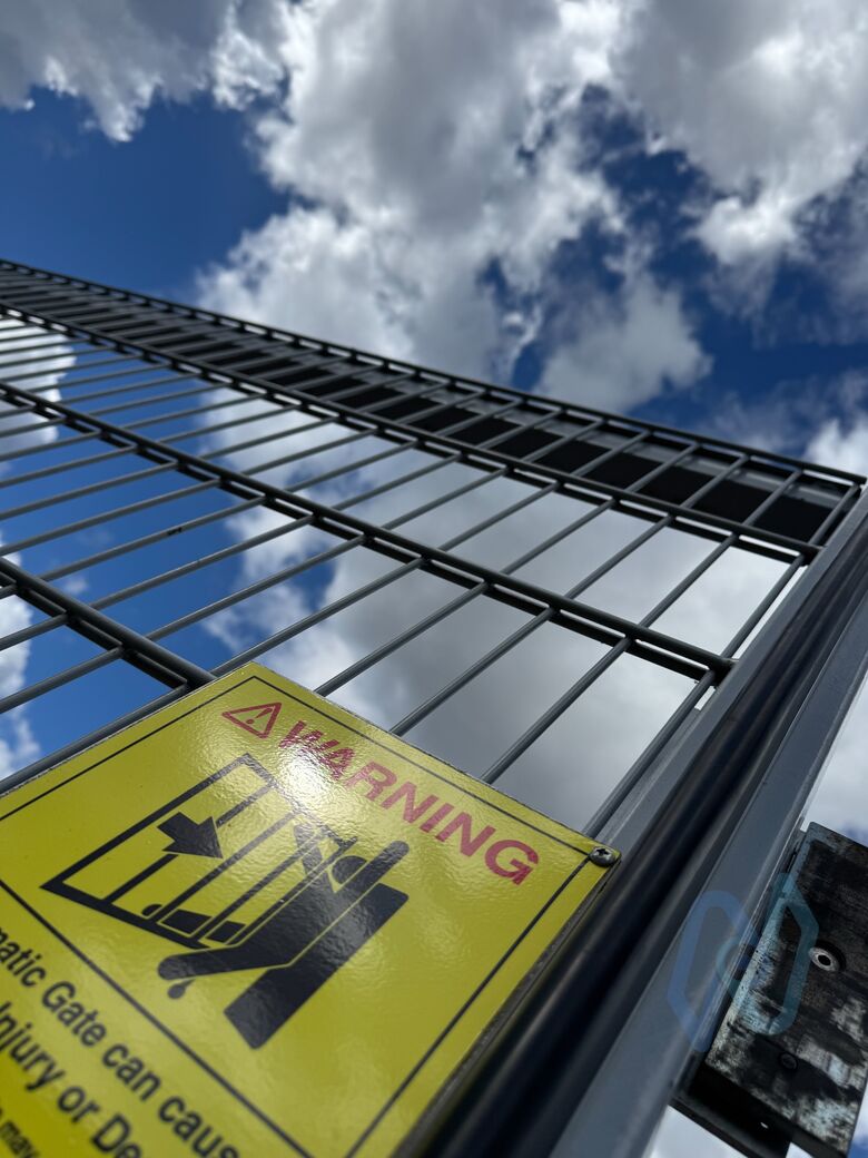 An automatic gate warning sign on the mesh gates