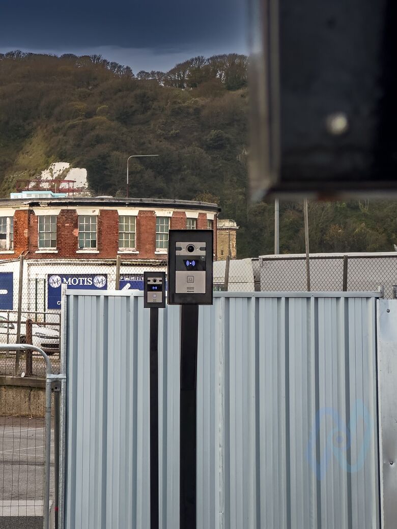 An intercom on a post at a lane at Motis Dover, with the Motis building behind