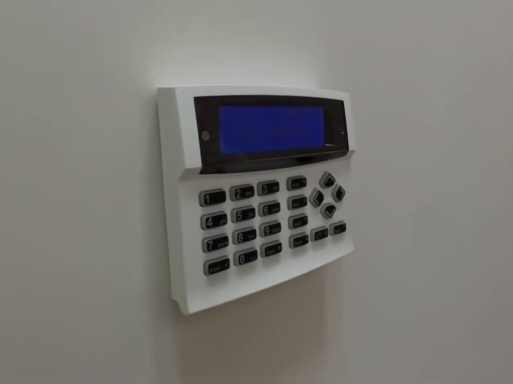 An Orisec intruder alarm keypad on a white wall