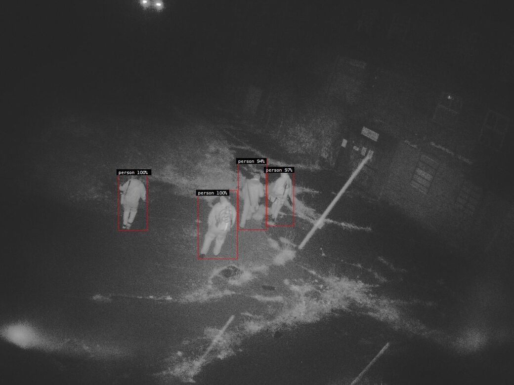 Night-time Reconeyez alarm photo of four people crossing a yard, each boxed as a person