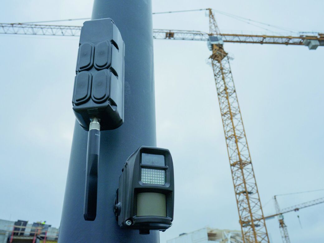 Reconeyez Bridge and detector on a pole at a construction site, with tower cranes behind