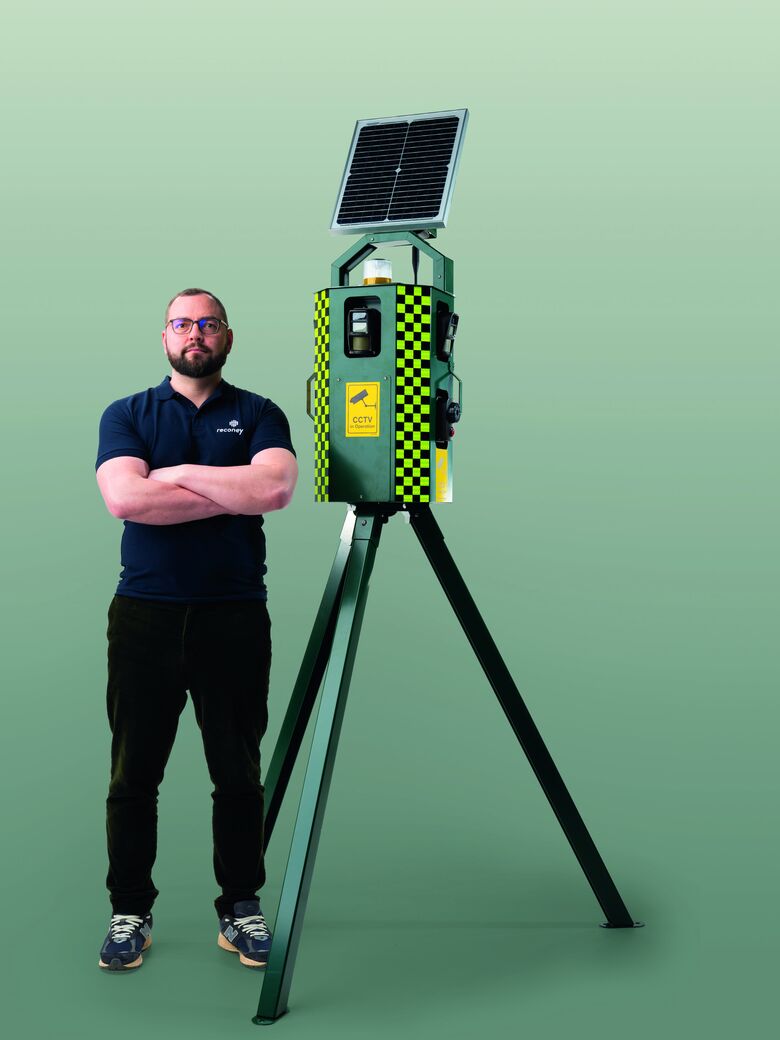 A man standing beside a Reconeyez Sentinel security tower on a tripod, for scale