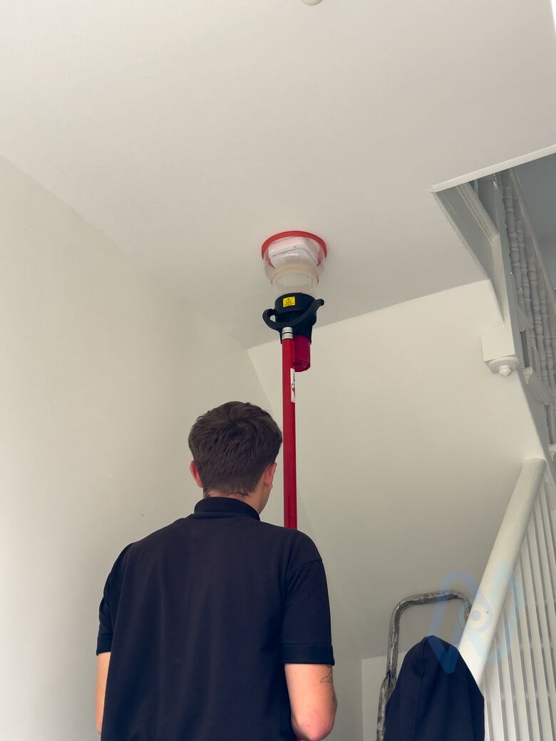 A Nova engineer smoke-testing a stairwell detector with a tester on a pole