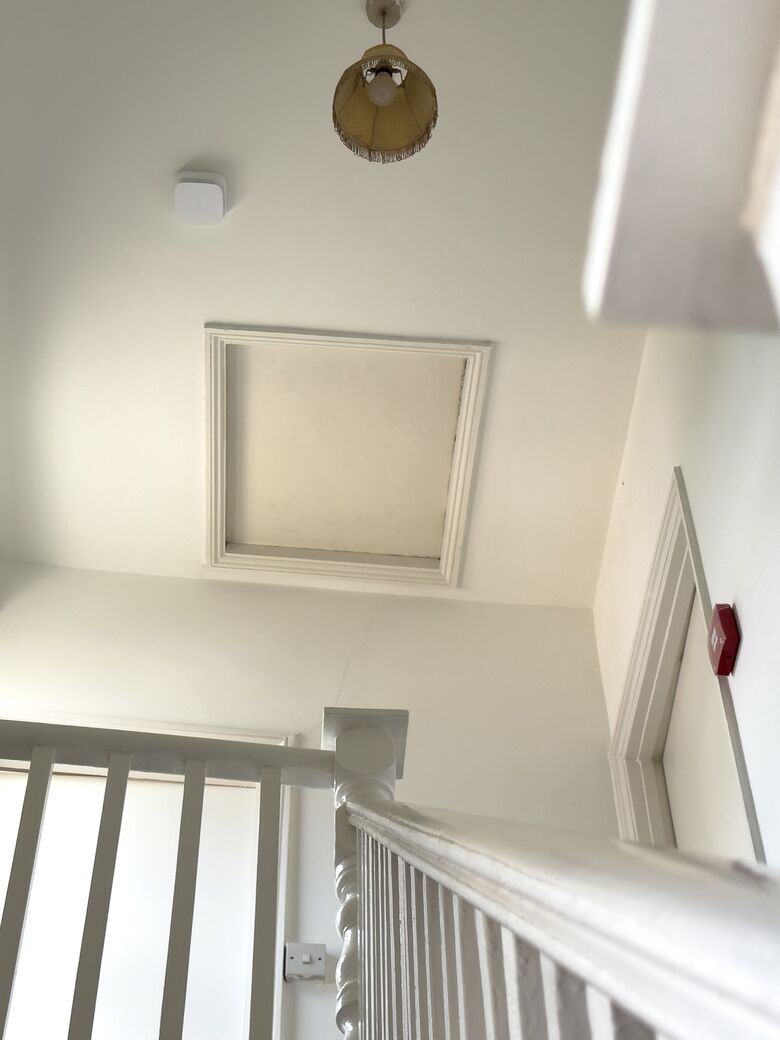 An Ajax EN54 detector on the stairwell ceiling of an HMO, with a call point beside the stairs